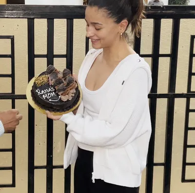 alia can t stop smiling as she cuts a cake with  raha s mom  written on it