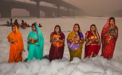 delhi  devotees stand in knee deep toxic foam in yamuna for chhath puja